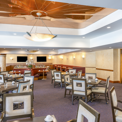 A spacious dining area with multiple tables, soft lighting, and neutral tones, perfect for a relaxed meal or gathering.