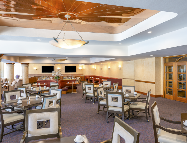 A spacious dining area with multiple tables, soft lighting, and neutral tones, perfect for a relaxed meal or gathering.