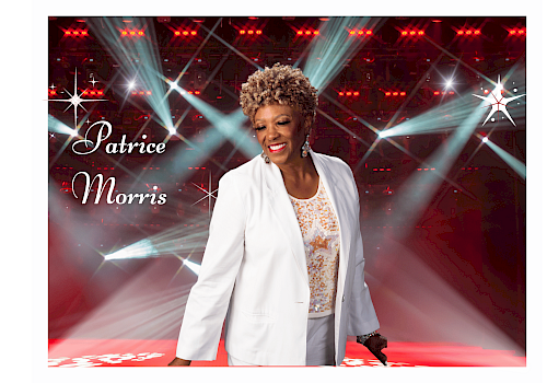 A smiling woman in a white blazer on a stage with bright lights; text reads “Patrice Morris” in cursive on the left.