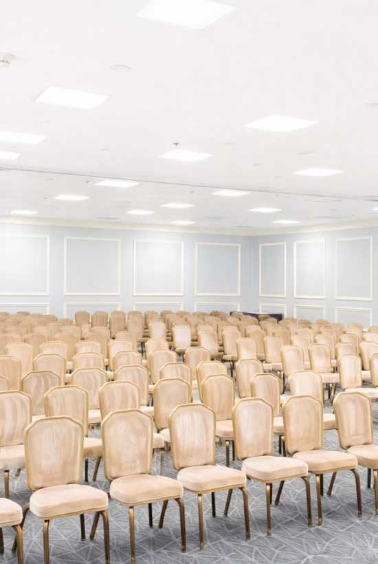 A large conference room with many beige chairs arranged in rows, ready for a seminar or meeting.