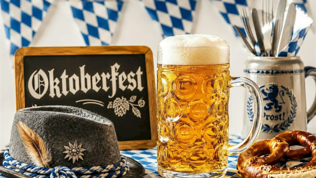 Oktoberfest scene with a beer stein, Bavarian hat, pretzel, and blue-and-white table decorations.
